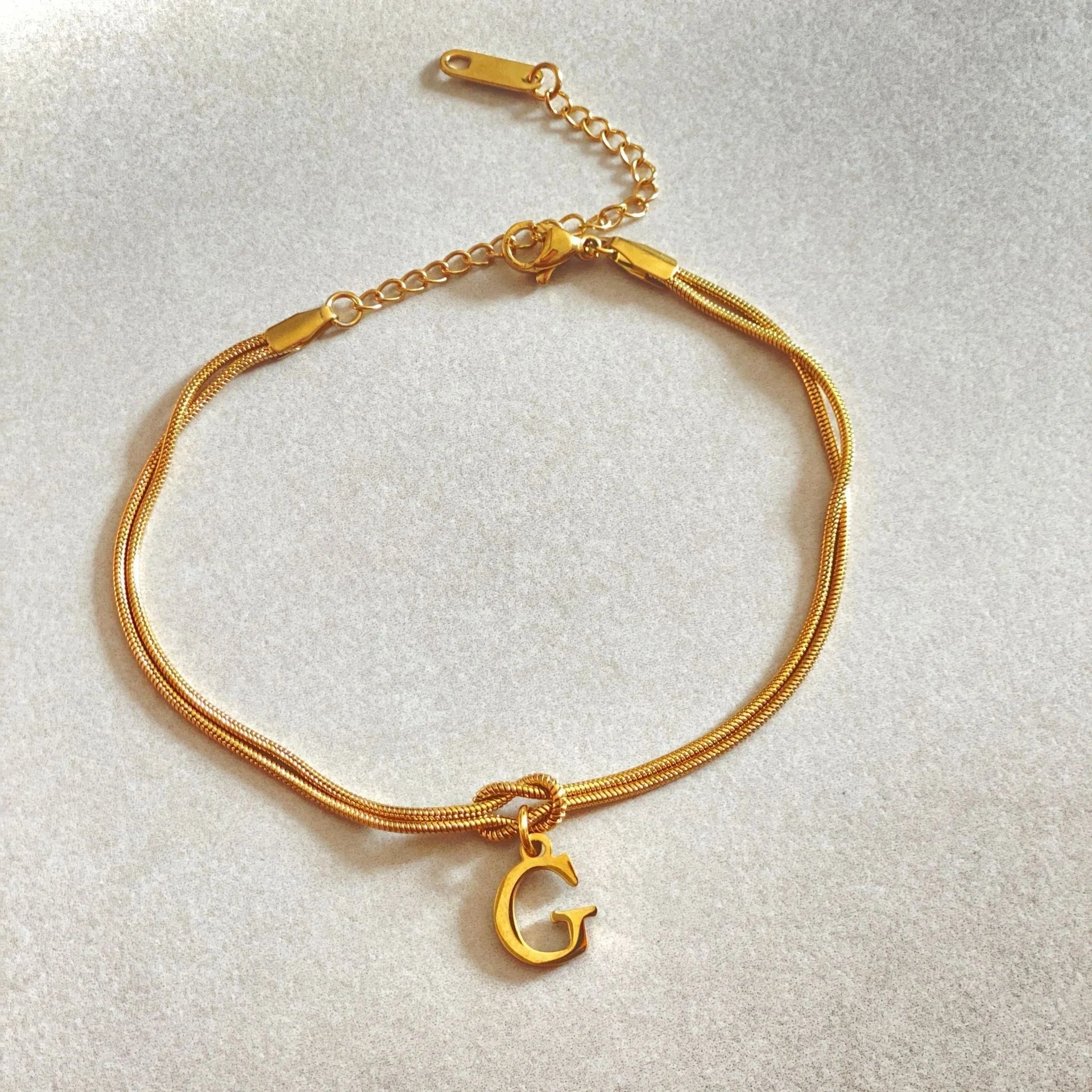 Elegant letter charm bracelets for women in gold and silver tones, featuring a delicate snake chain design and personalised letter charms.