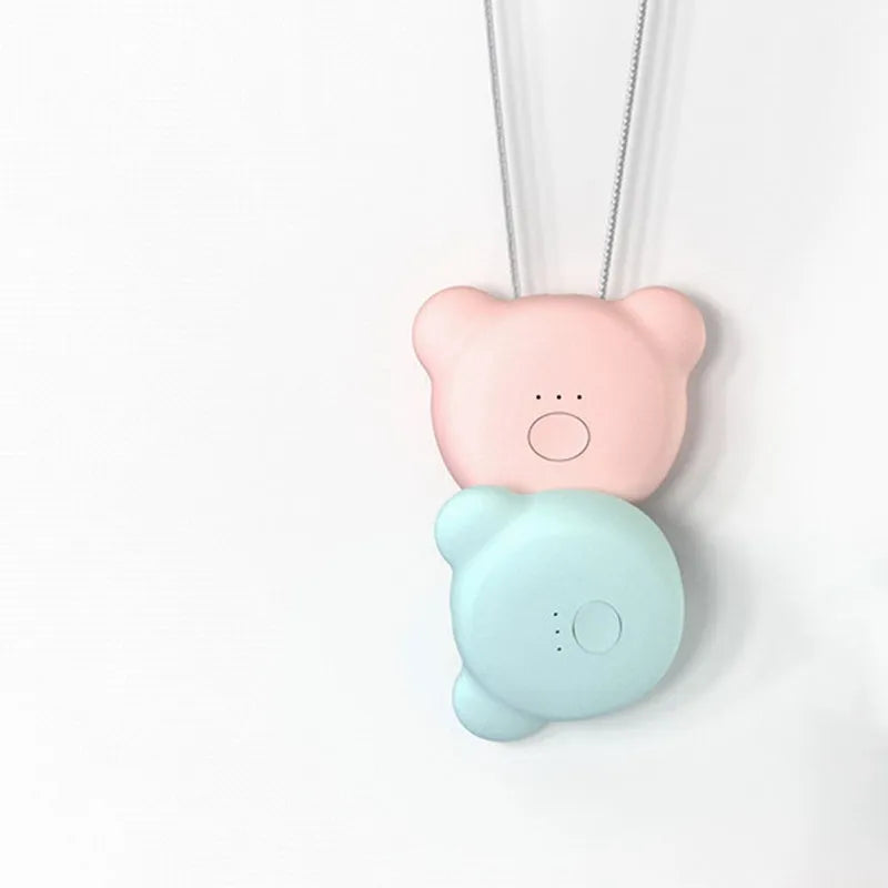 Small pink wearable air purifier pendant on a necklace, showing USB charging port and single button.