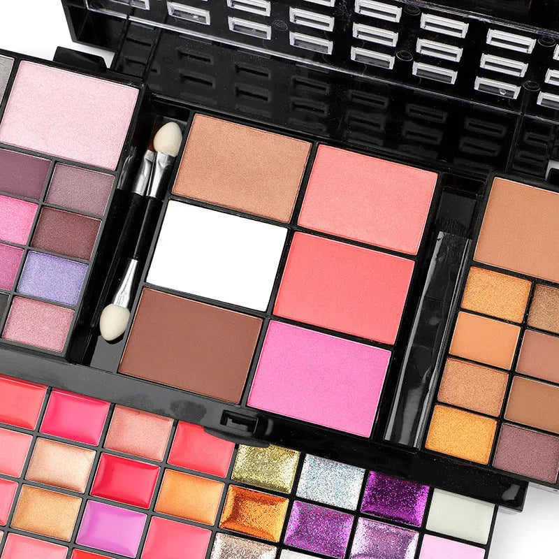 Open 74 colour makeup combination palette showing four layers of eyeshadow, lip gloss, blush and contour powders with brushes.