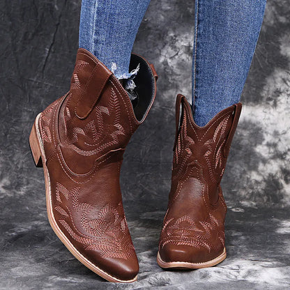 Blue women's cowboy ankle boots with embroidery and a low wedge heel on a wooden floor.