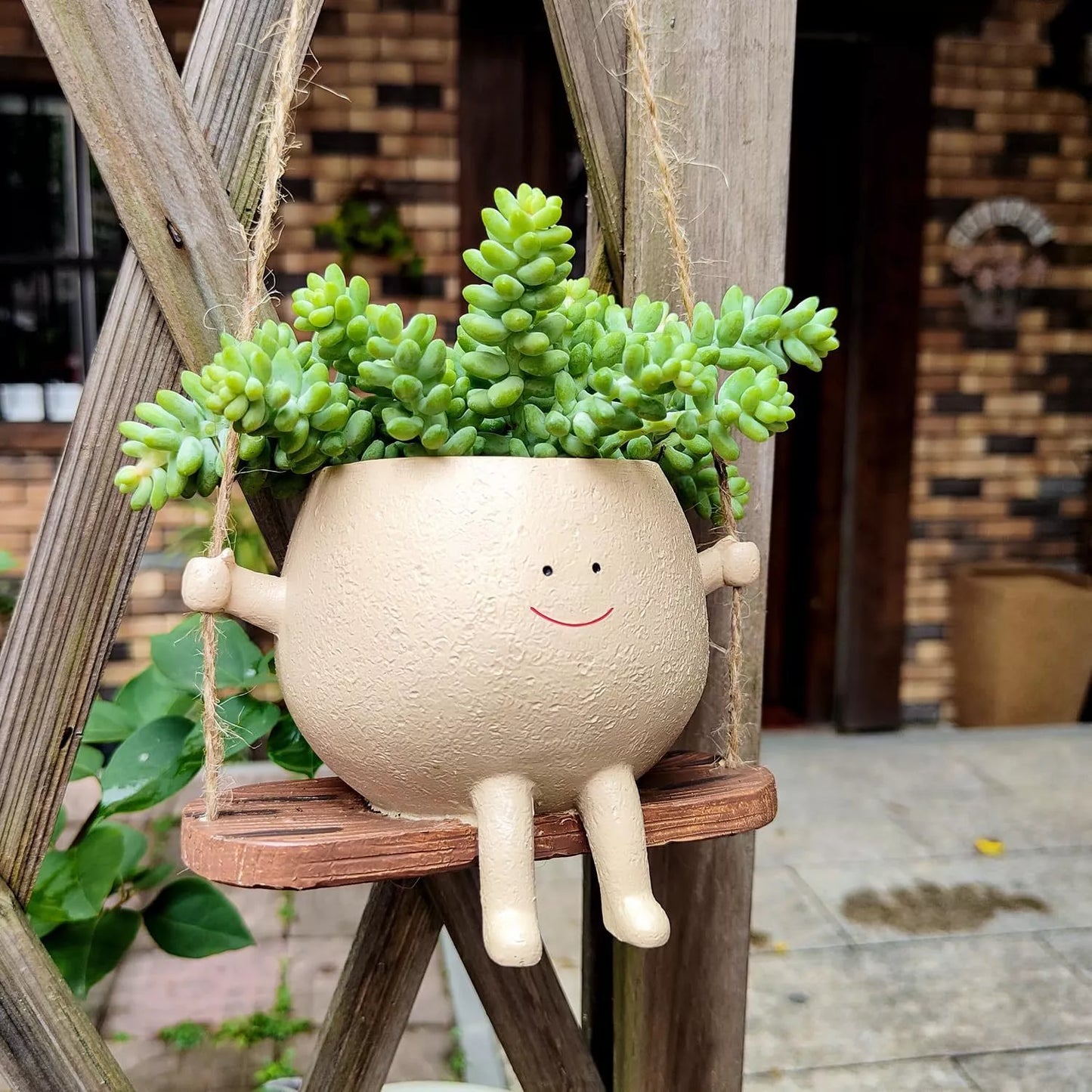 Swing face hanging flower pot with child's smiling design, made of durable resin