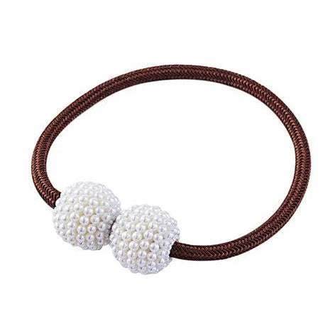 Magnetic curtain tiebacks with white pearl beads and fabric loops holding gathered curtain