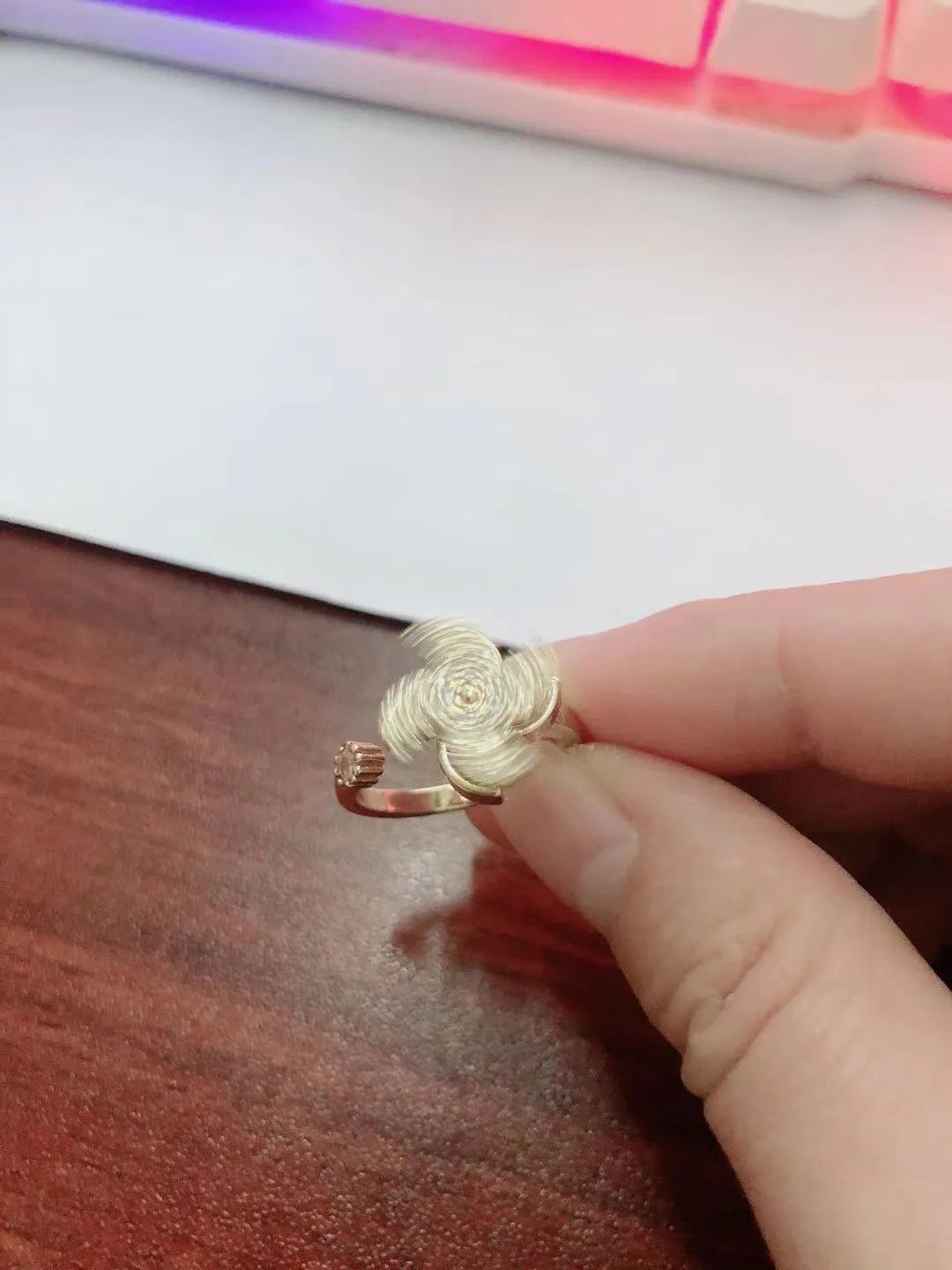 Gold and silver kinetic rings showing a geometric copper band with a central spinning windmill detail.