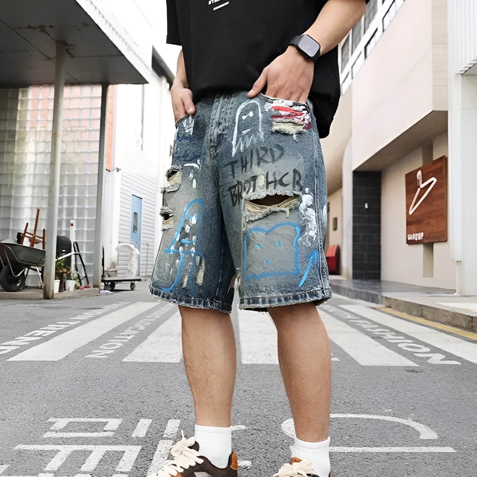 Blue men's jeans shorts with ripped distressed detailing and graffiti design, straight leg cut with zipper fly