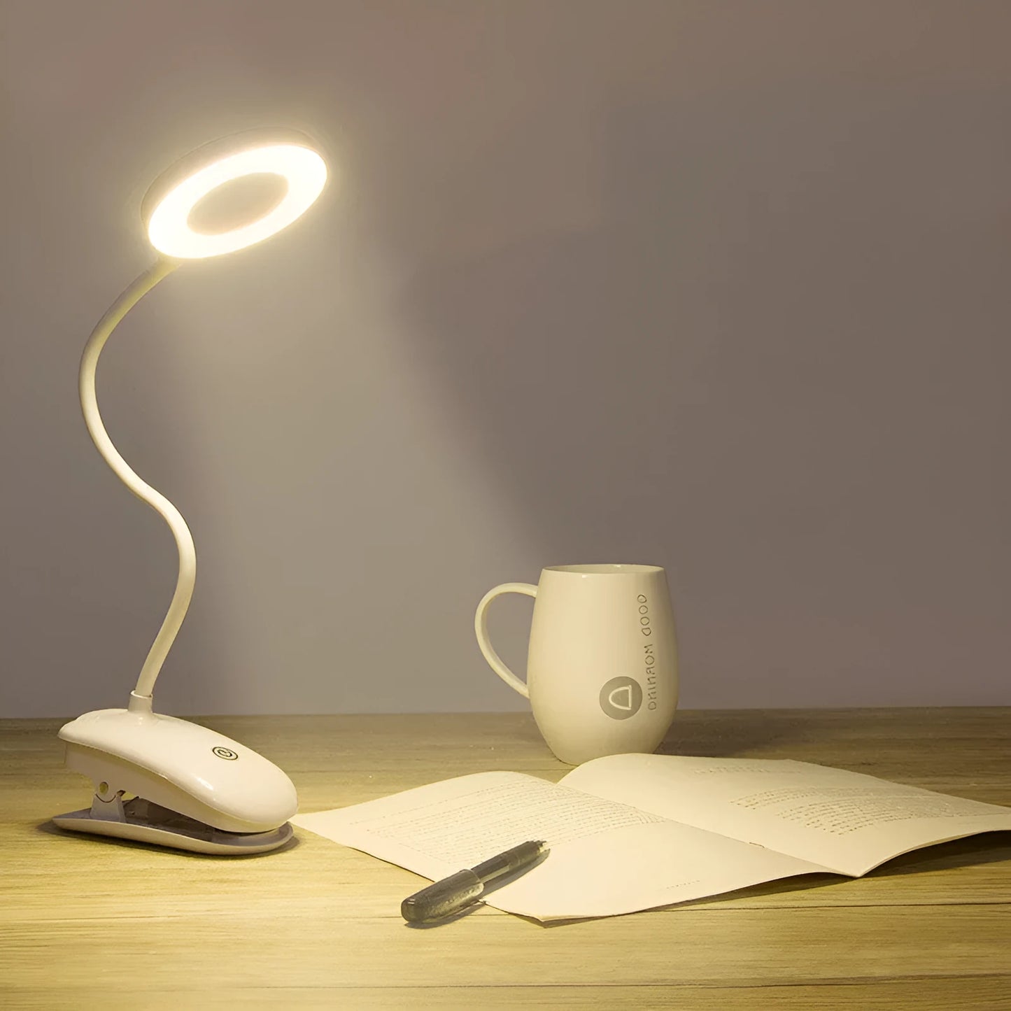 A modern white clip-on rechargeable desk lamp with a touch-sensitive switch and a plastic shade.