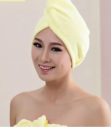 A woman wearing a sky blue microfiber hair dryer cap, with wet hair tucked inside, showing the towel's wrap-around design.