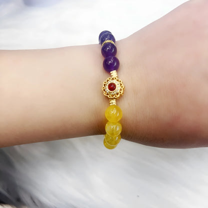 Handmade women's bracelet with yellow and purple amethyst crystals on wrist.