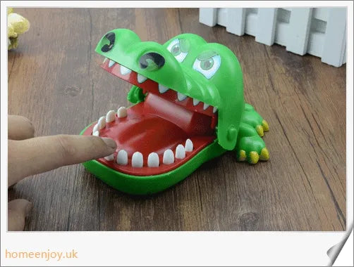 A bright green crocodile with big eyes and long teeth, ready to bite down on the dentist's tongs.