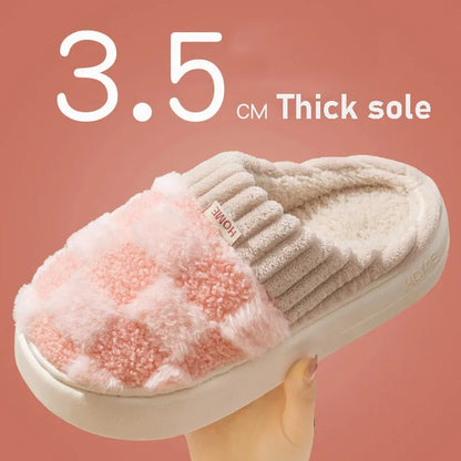 Plaid pattern women's plush slippers with coral velvet upper and textured PVC sole on a wooden floor.