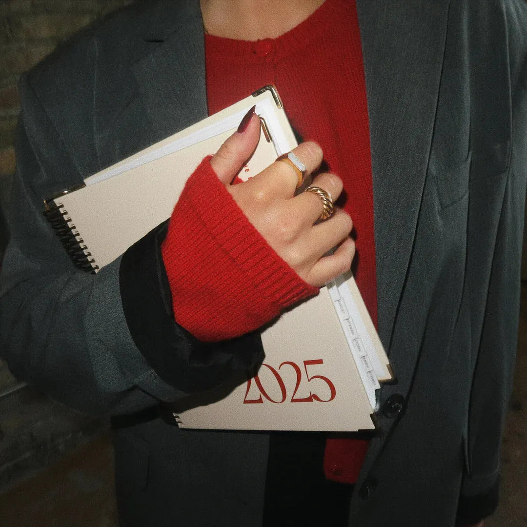 Cherry red A5 daily schedule coil notebook with spiral binding lying open.