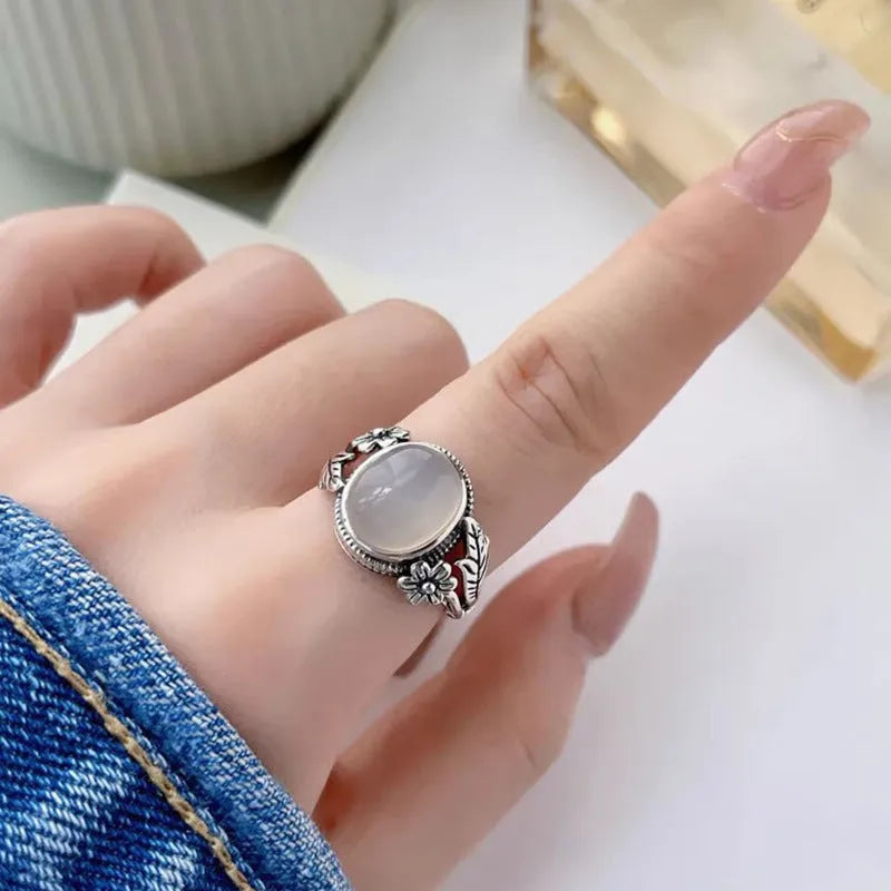 Adjustable open-mouth copper vintage ring with U-shape and antiqued white chalcedony-style finish on a wooden surface.
