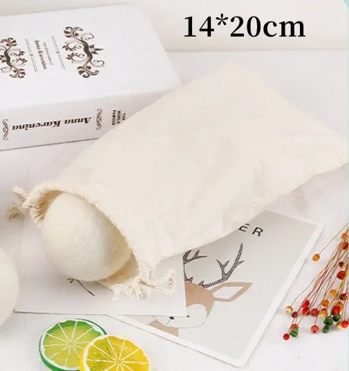 A 100% wool drying ball for laundry next to a plain cotton storage bag on a background.