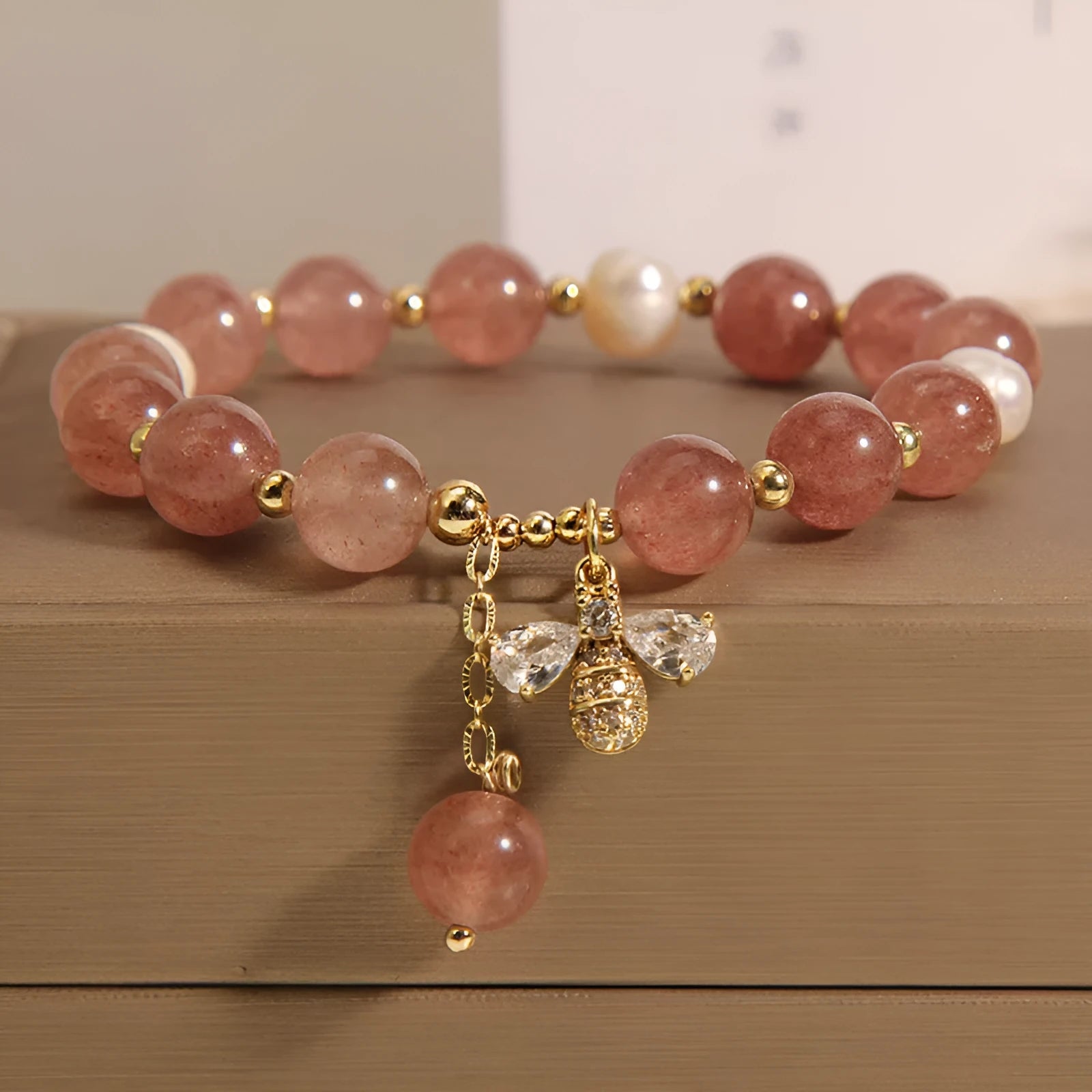 Women's adjustable bracelet with freshwater pearls, strawberry quartz stones, and bee charm