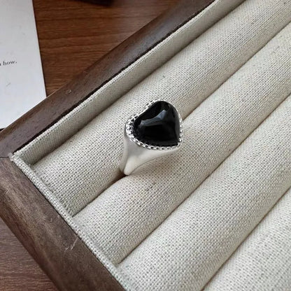 Adjustable sterling silver ring with a heart-shaped black agate stone in a niche setting on a woman's finger.