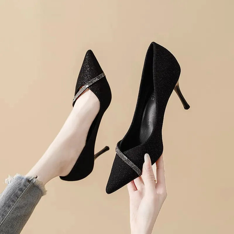 Gold women's stiletto high heels with pointed toe on a plain background.