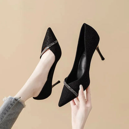 Gold women's stiletto high heels with pointed toe on a plain background.