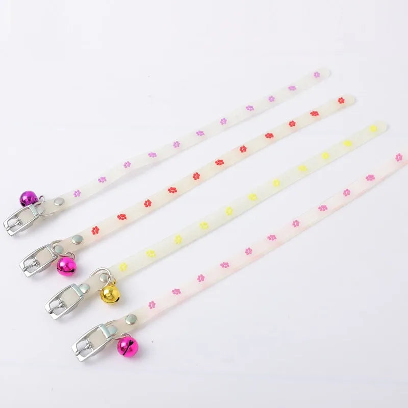 Glowing adjustable luminous collar for cats on a dark background, showing silicone chain and metal bell.
