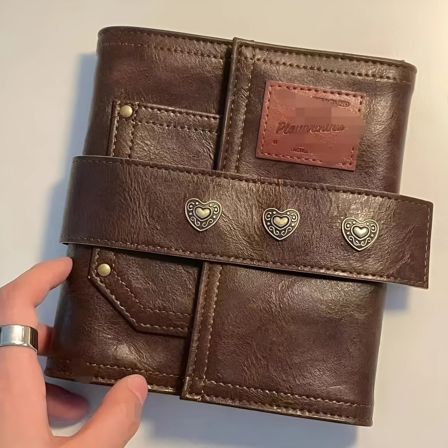 Brown A7 loose-leaf notebook with PU cover and retro buckle design, shown open.