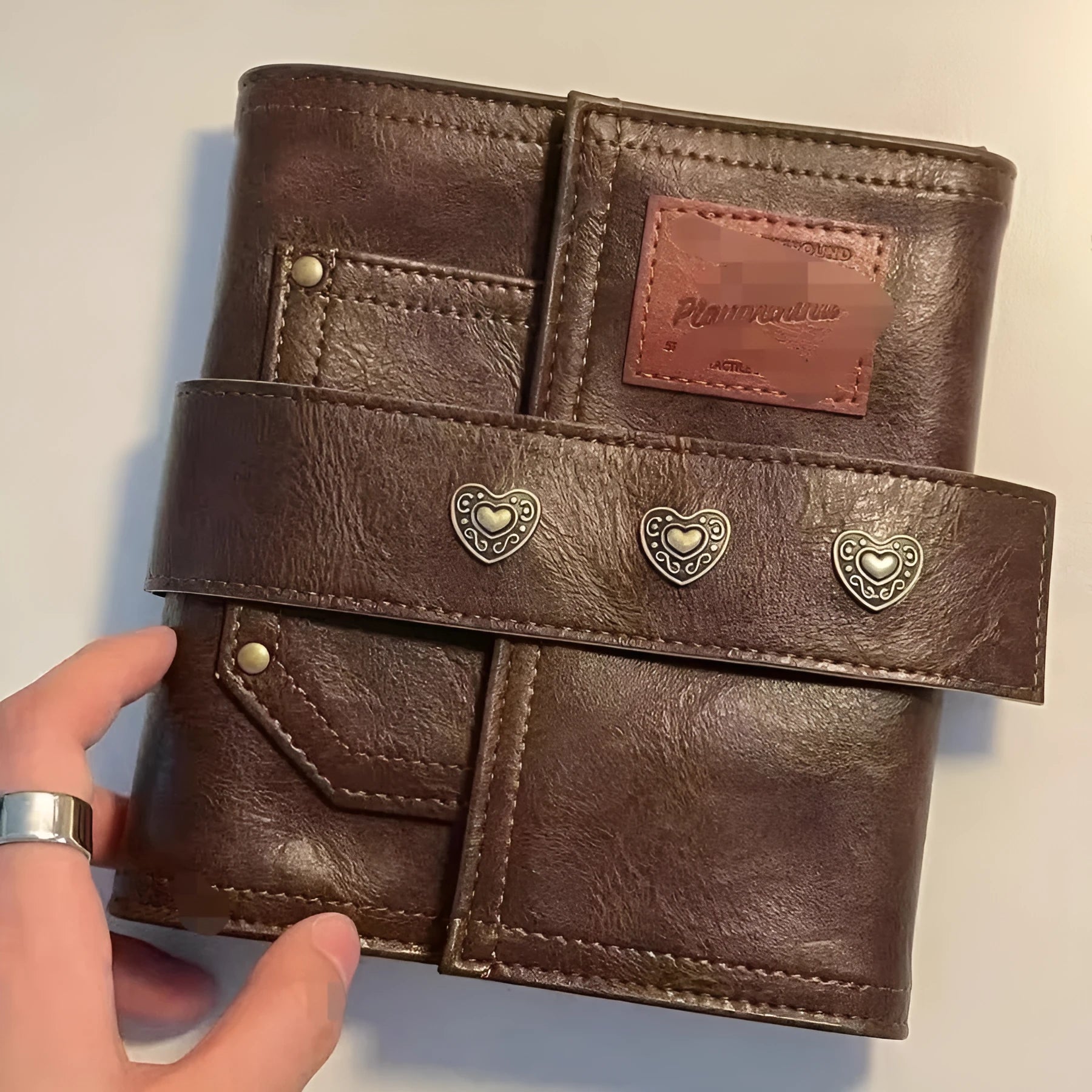 Brown A7 loose-leaf notebook with PU cover and retro buckle design, shown open.