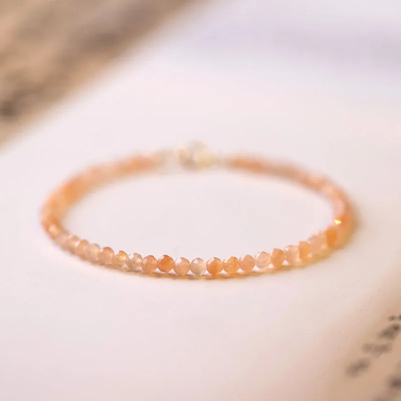 Women's ultra-thin 3mm Sunstone bead bracelet on wrist, showing natural crystal and delicate design.
