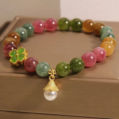 Colourful mixed-material women's bracelet with a four-leaf clover charm and a pearl pendant on a geometric chain.