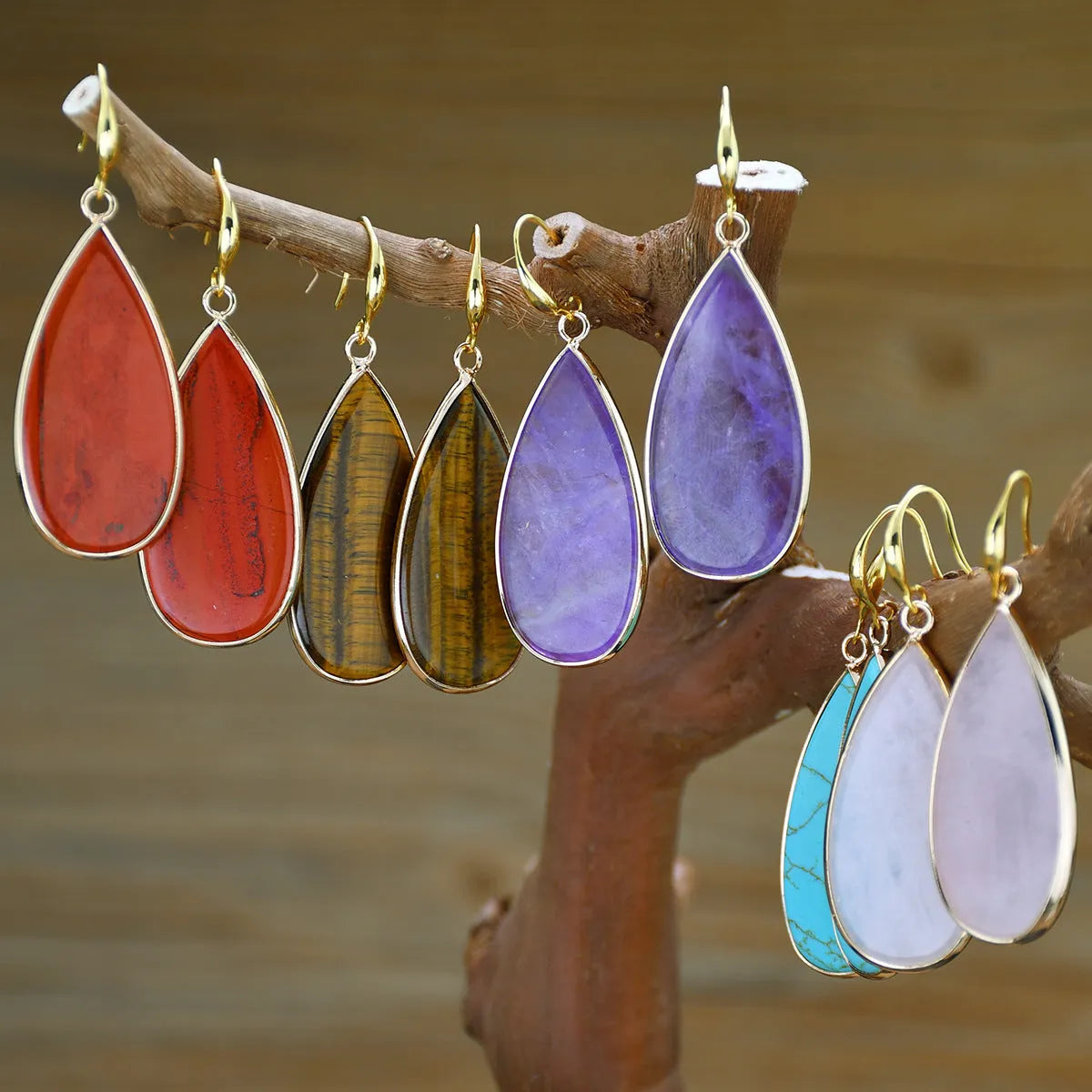 Handmade vintage long water drop earrings with tigereye stone and sterling silver hooks on a textured background.