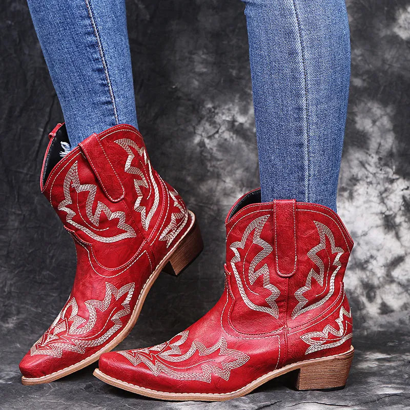 Blue women's cowboy ankle boots with embroidery and a low wedge heel on a wooden floor.