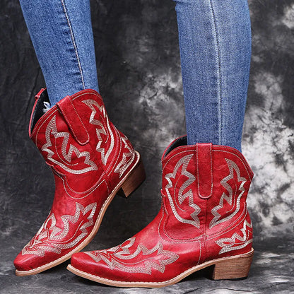 Blue women's cowboy ankle boots with embroidery and a low wedge heel on a wooden floor.