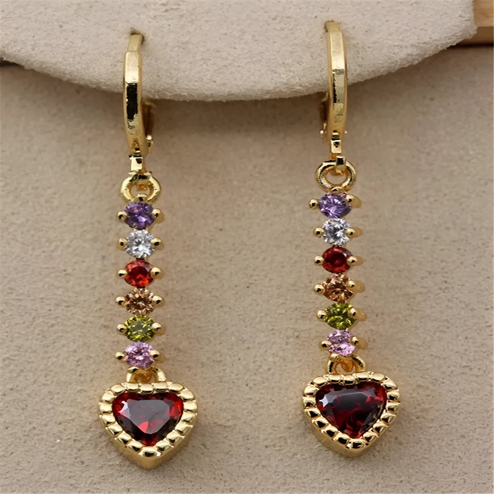 A pair of small gold-coloured heart-shaped alloy earrings on a plain background.