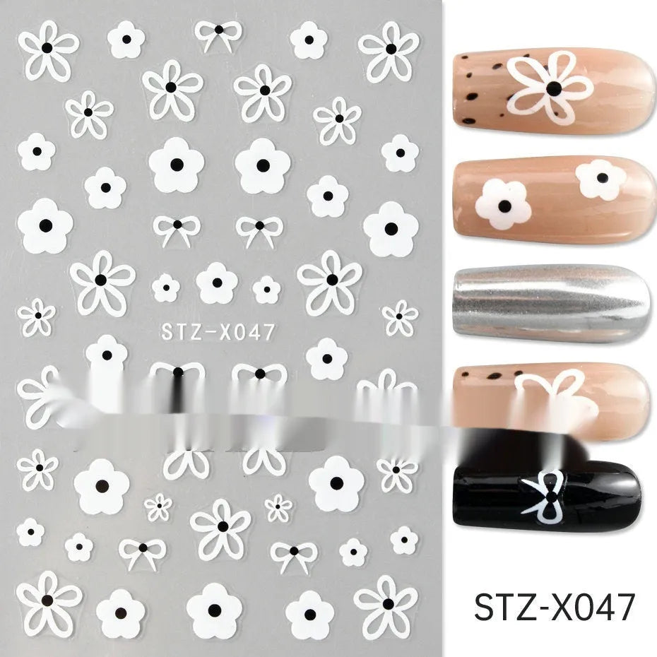 Assortment of black and silver nail sticker designs including cartoon and French tip patterns on a plastic sheet.