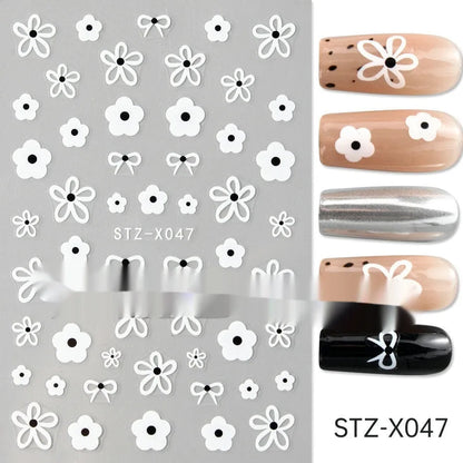 Assortment of black and silver nail sticker designs including cartoon and French tip patterns on a plastic sheet.
