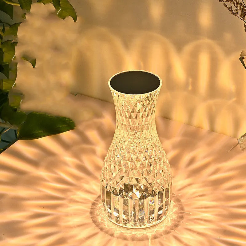 Vase-shaped crystal table lamp with remote control on a bedside table, showing diamond-like glow and USB charging port.