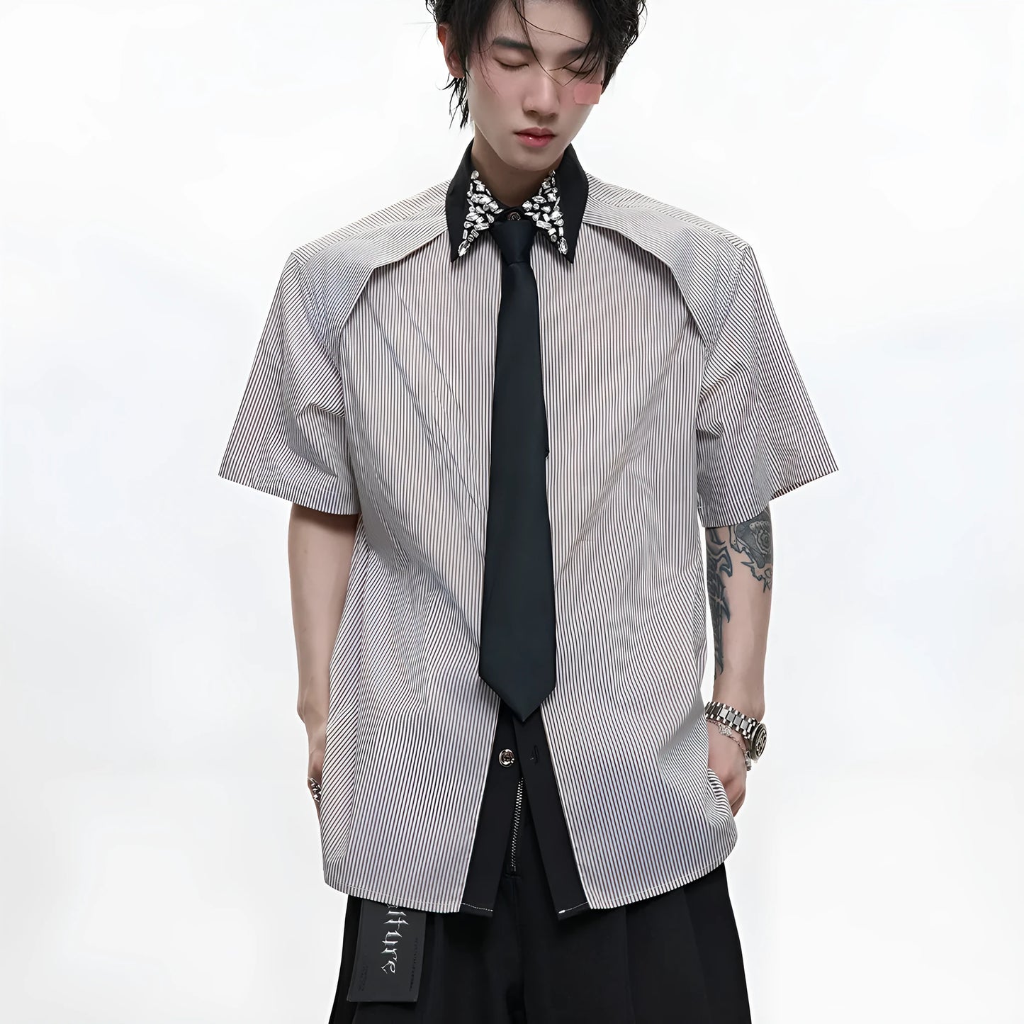 Man wearing a blue loose fit men's shirt with a diamond tie collar and patchwork striped design.