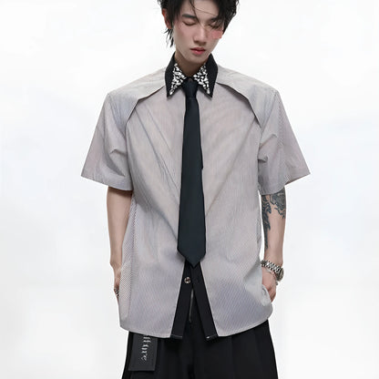 Man wearing a blue loose fit men's shirt with a diamond tie collar and patchwork striped design.