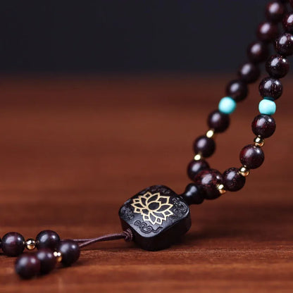 Zambia rosewood bead bracelet with 108 beads and flat lotus pendant on wooden surface