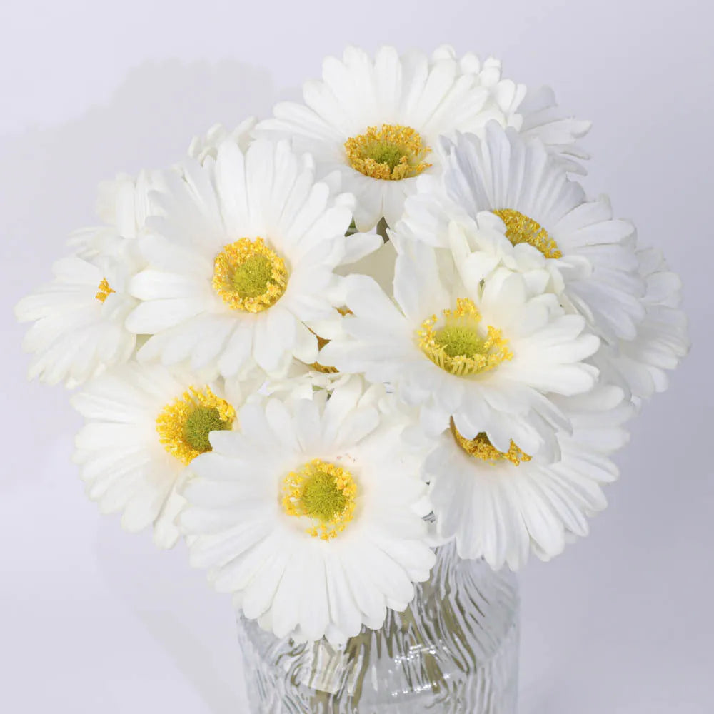 Silk artificial flower bouquet in a white polyurethane pot on a wooden table.