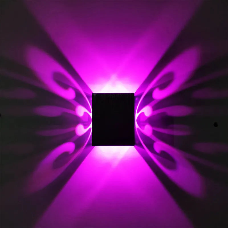 Modern aluminium butterfly-shaped LED wall lamp with colour-changing lights on a plain wall