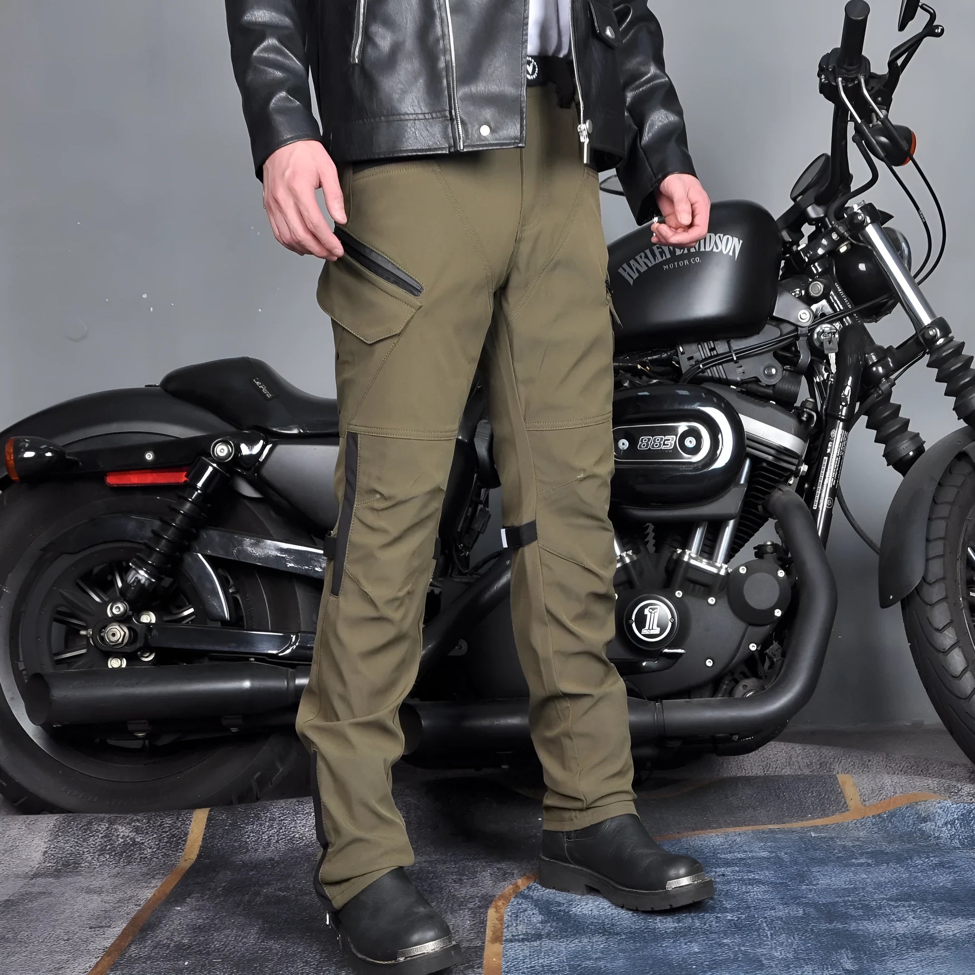 Motorcycle rider wearing green waterproof trousers with removable protective armour on knees and hips.