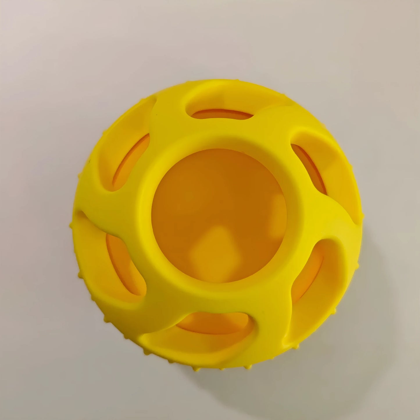Yellow silicone pet slow feeding ball with treat-dispensing moulded interior for dental cleaning