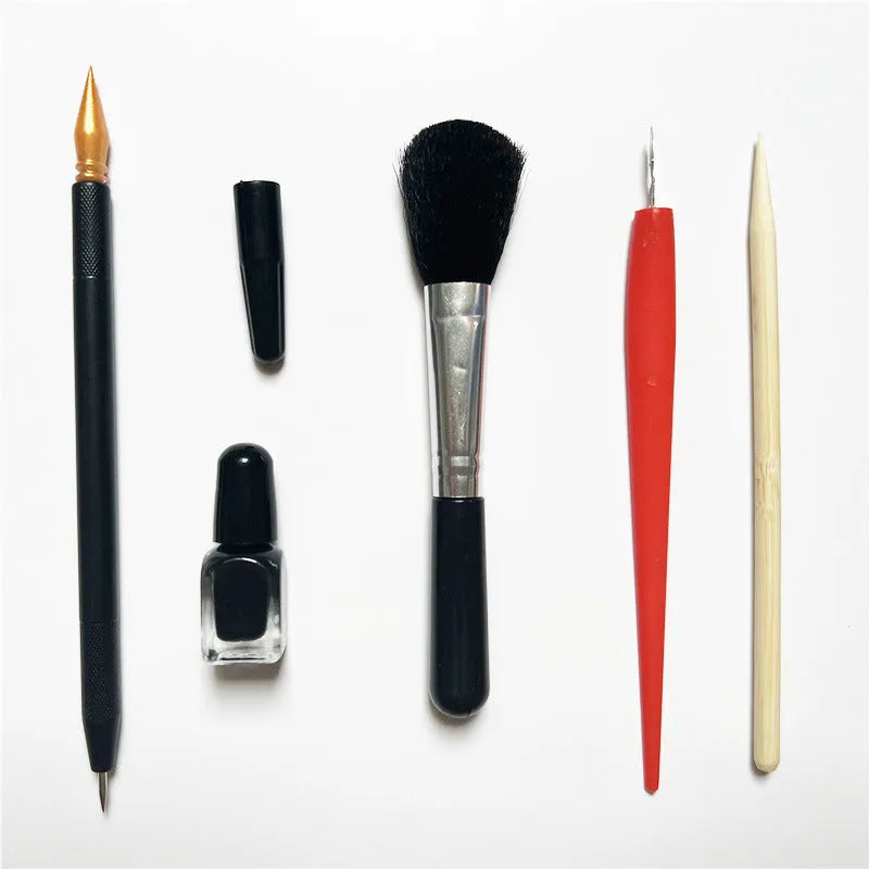 Diamond painting repair tool set with metal scraper pen, bottle of adhesive liquid, soft brush, and bamboo stick on a craft table