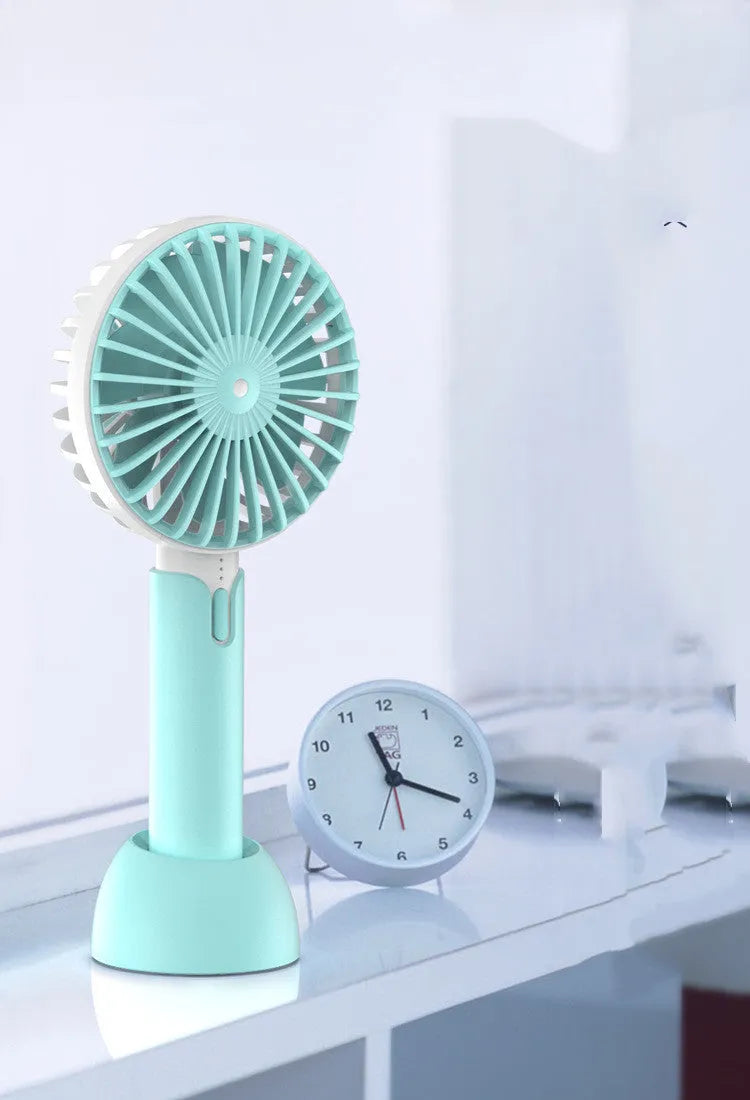 Blue handheld and desktop mini USB electric fan with three-speed control on a table.