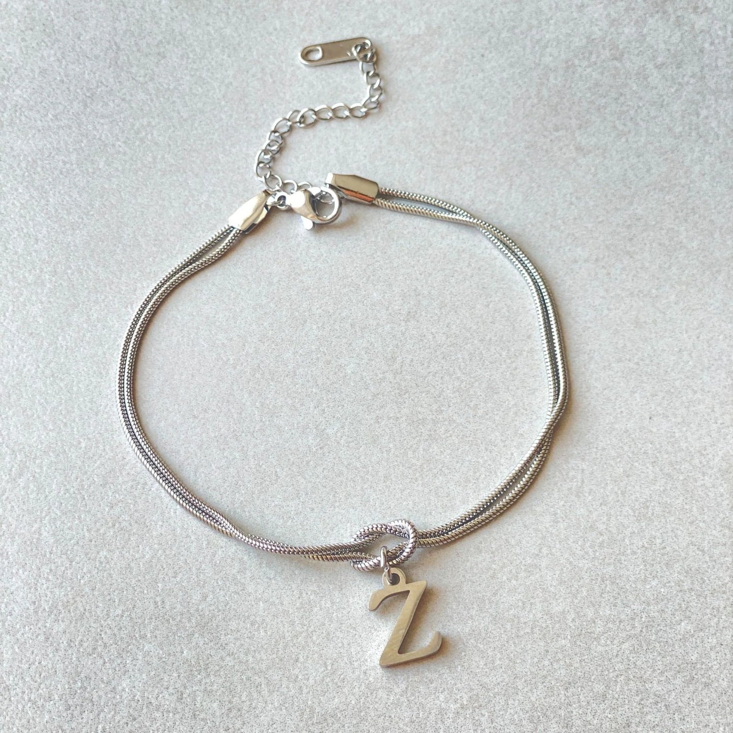 Elegant letter charm bracelets for women in gold and silver tones, featuring a delicate snake chain design and personalised letter charms.