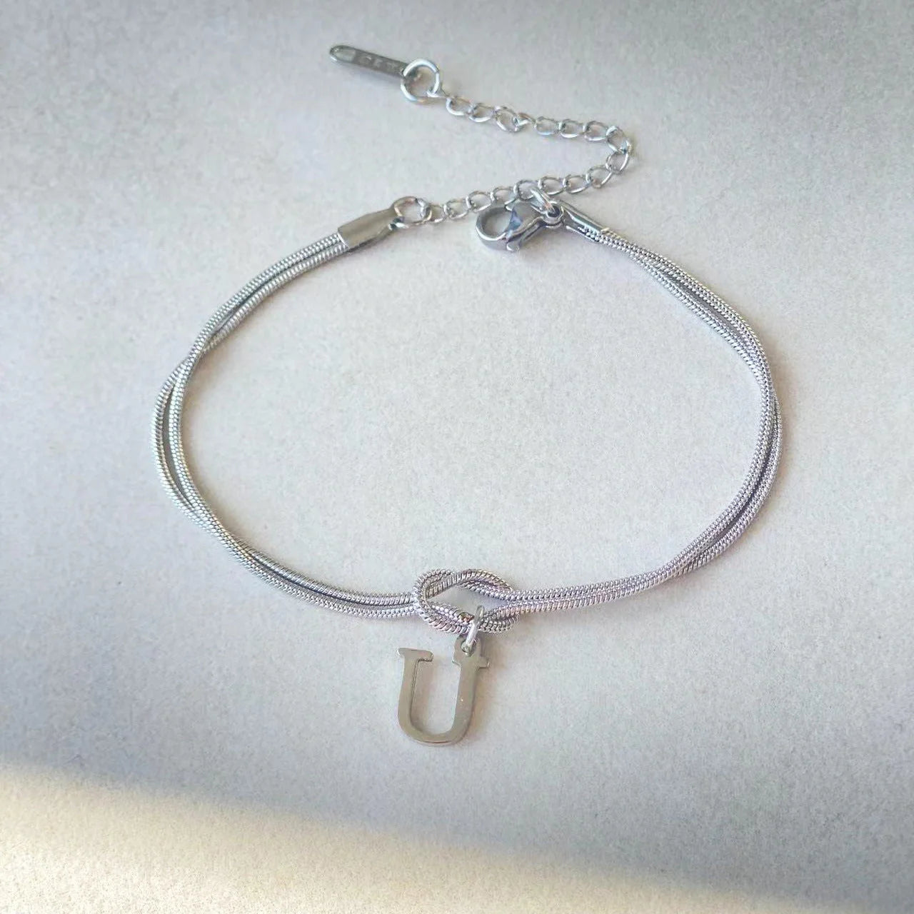 Elegant letter charm bracelets for women in gold and silver tones, featuring a delicate snake chain design and personalised letter charms.