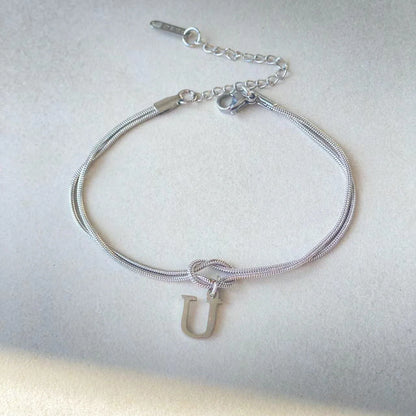 Elegant letter charm bracelets for women in gold and silver tones, featuring a delicate snake chain design and personalised letter charms.