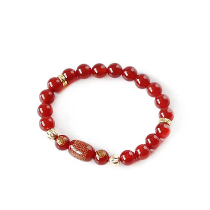 A red agate beaded bracelet with a Guanyin pendant on a white background.