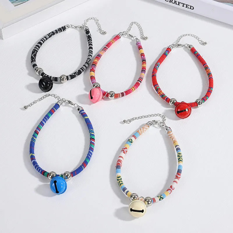 Coloured ethnic pattern adjustable dog collar with metal bell and reflective strip on a nylon strap.
