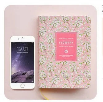 Green floral notepad with fabric imitation leather cover lying open on a table.