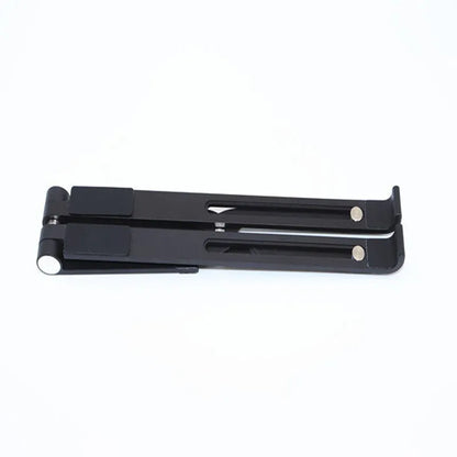Black aluminium laptop stand on a wooden desk next to a notebook