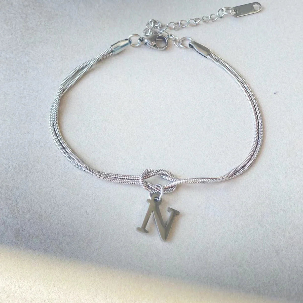 Elegant letter charm bracelets for women in gold and silver tones, featuring a delicate snake chain design and personalised letter charms.