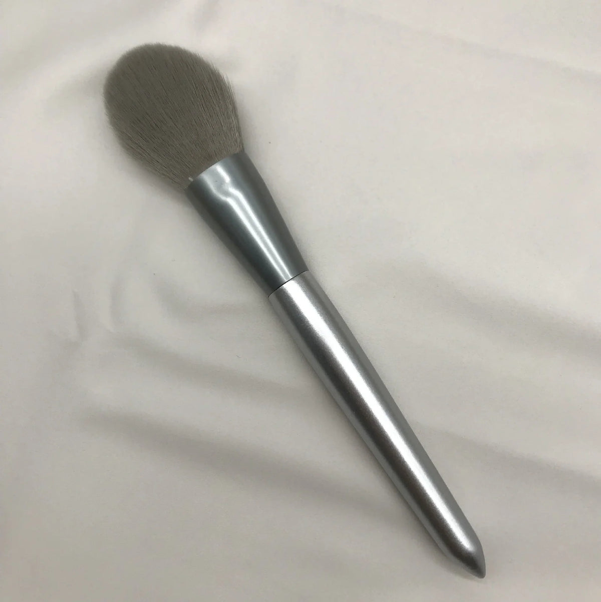 10 makeup brushes with moonlight silver finish and wooden handles beside PU brush bag